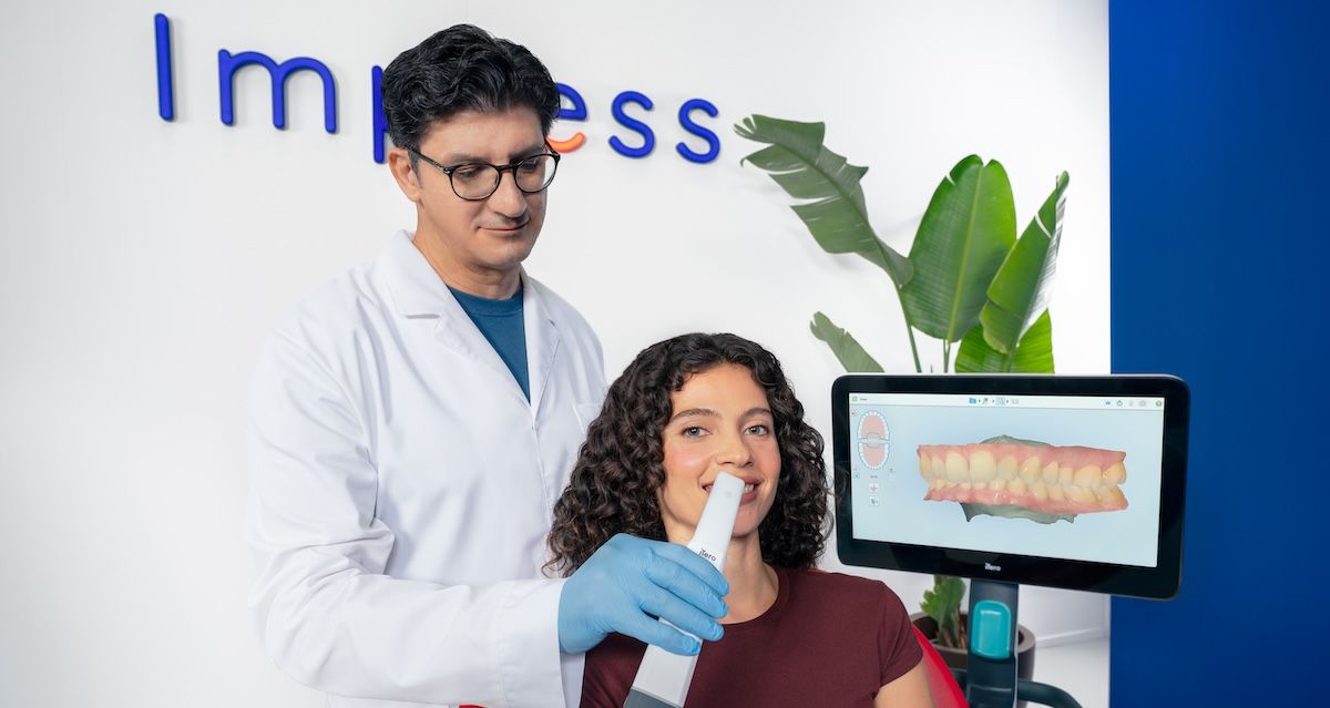 Een orthodontist maakt een 3D-scan van een patiënt in een Impress-ruimte.