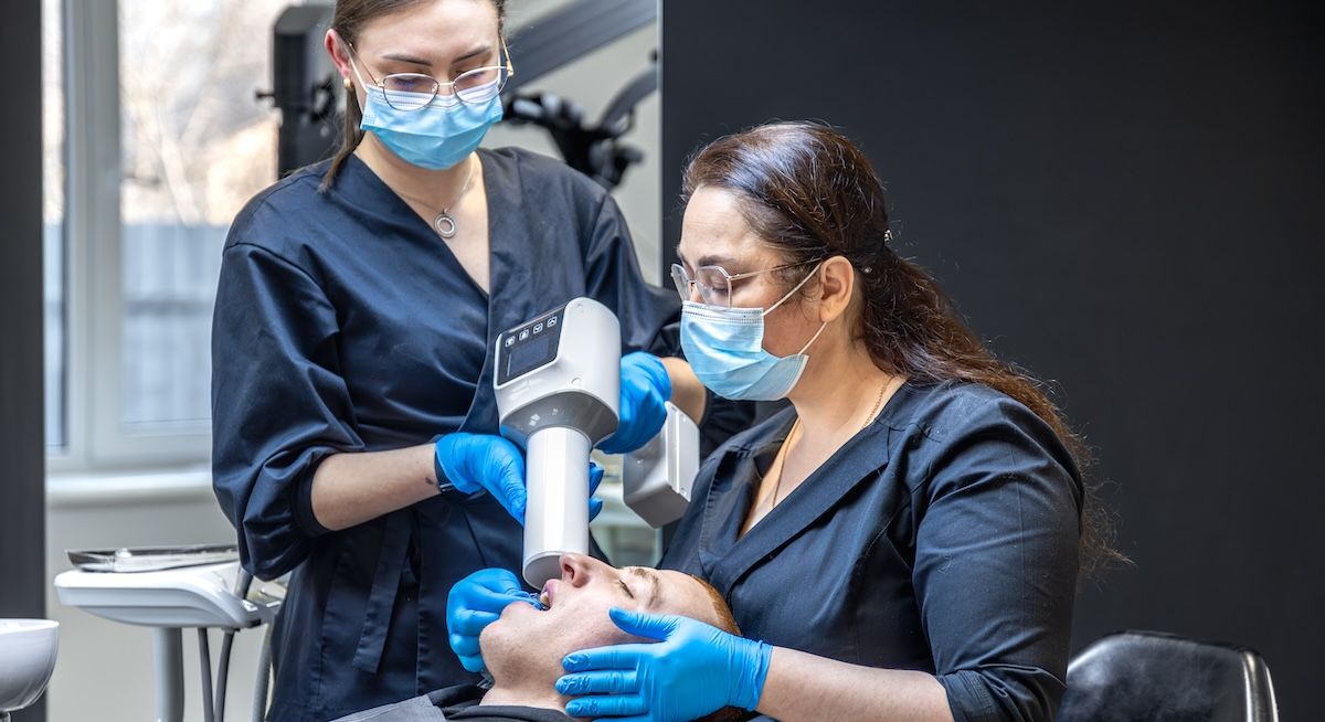 twee tandarts vrouwen die een scan maken van het gebit van een man