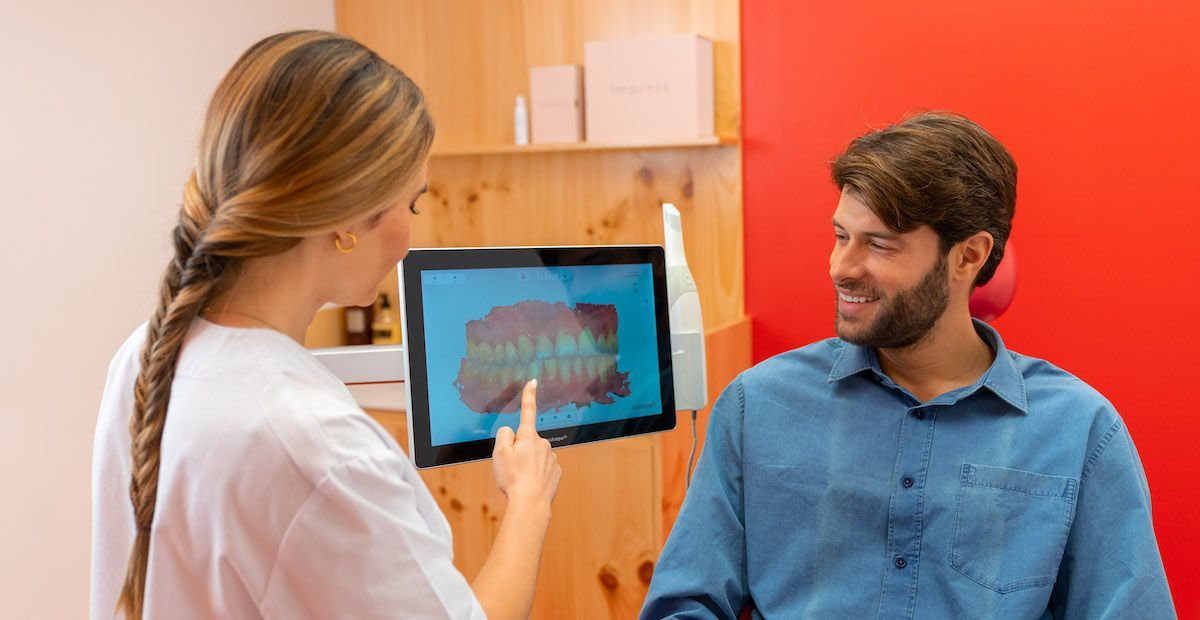 Een arts toont een patiënt de 3D-scan van zijn gebit. 