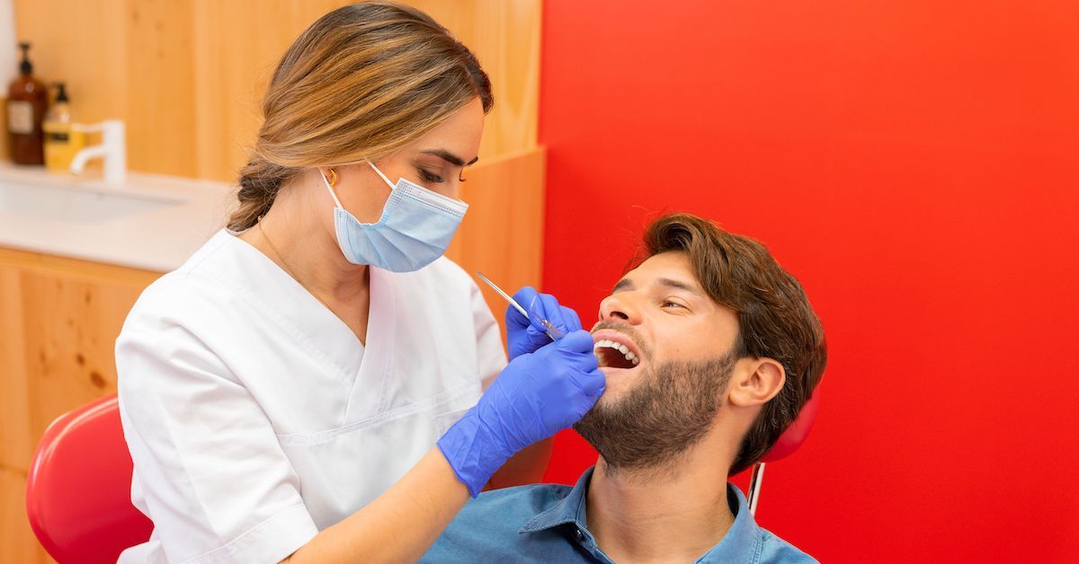 Dentist performing root planing and scaling on male patient