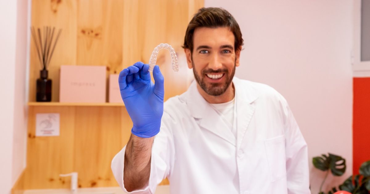 tandarts lachend met een aligner in zijn hand