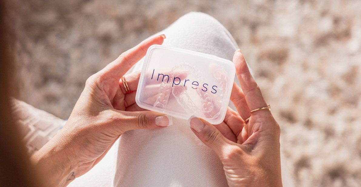 Meisje houdt haar Impress clear aligners-etui met beide handen vast.&nbsp;