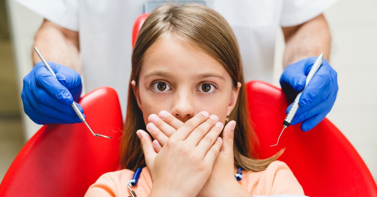 Een meisje bedekt haar mond met beide handen en kijkt bang.&nbsp;