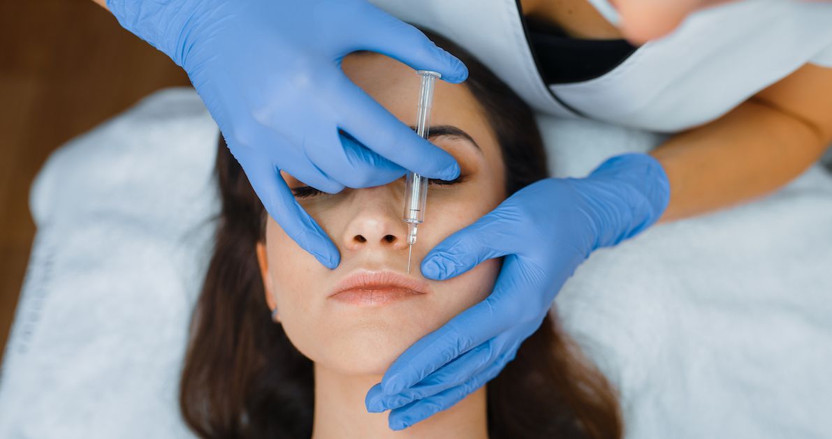 Arzt verabreicht Botox an der Oberlippe eines Patienten.