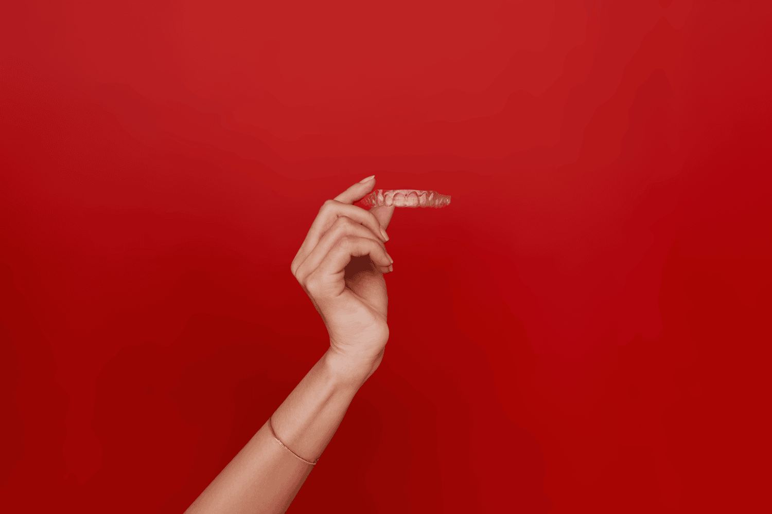 Рука, що тримає прозорі вирівнювачі Impress 