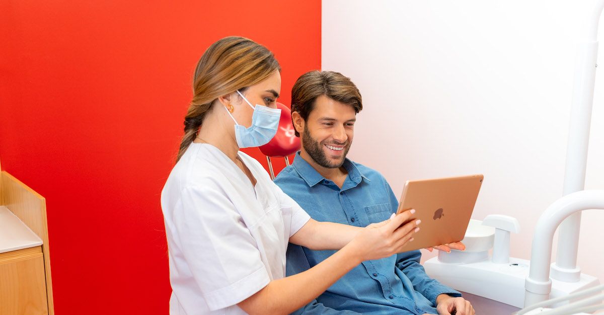 Ein Arzt zeigt einem Patienten in einer Impress-Praxis ein Tablet.