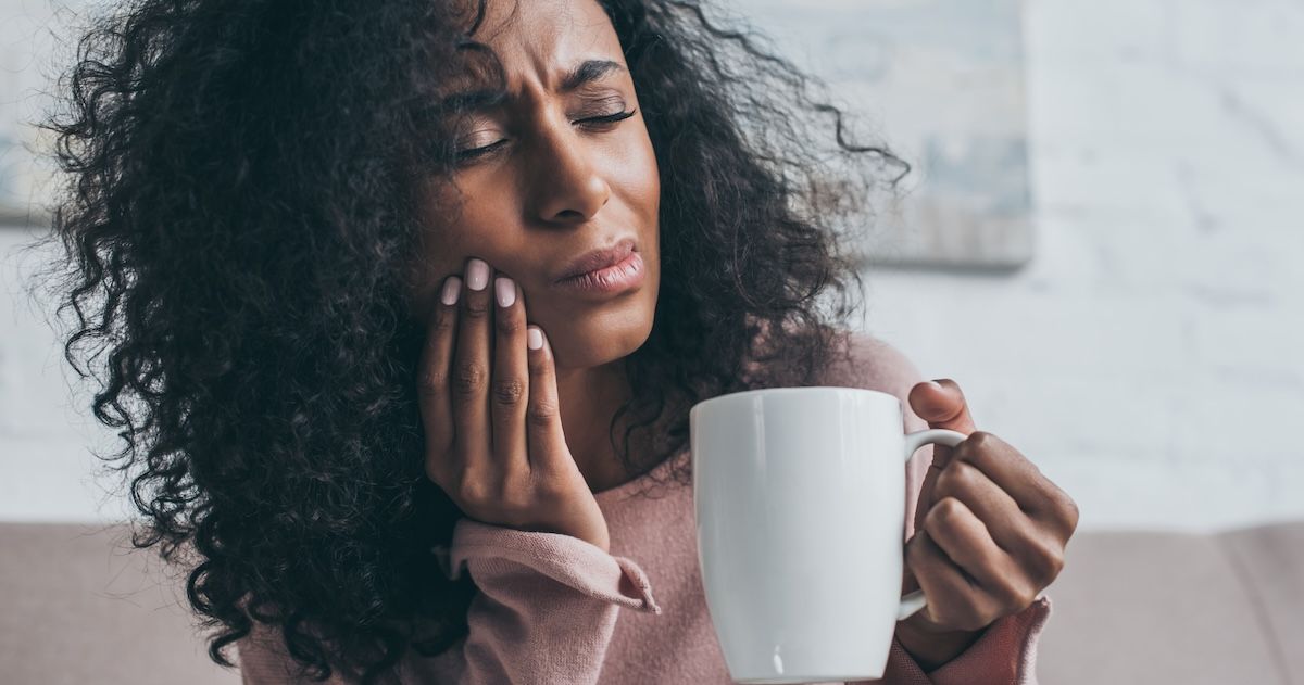 vrouw met een warm drankje om haar pijn in der tanden te verhelpen