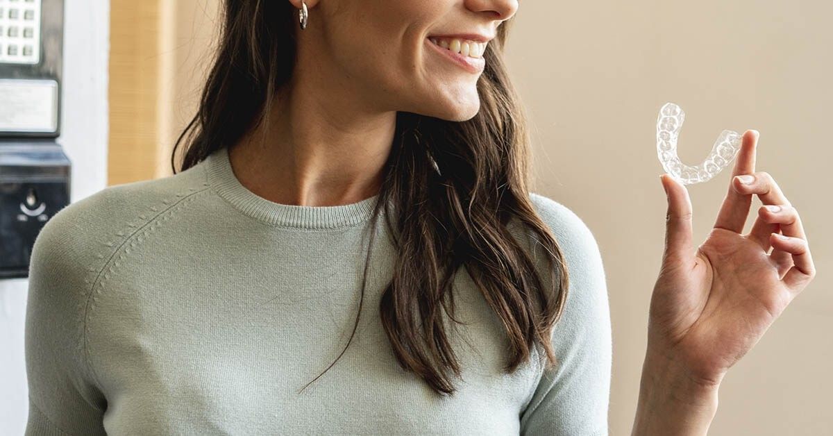 Patient holding Impress invisible aligner and smiling