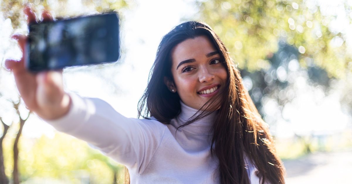 vrouw die aan het lachen is naar een telefoon en maakt een selfie