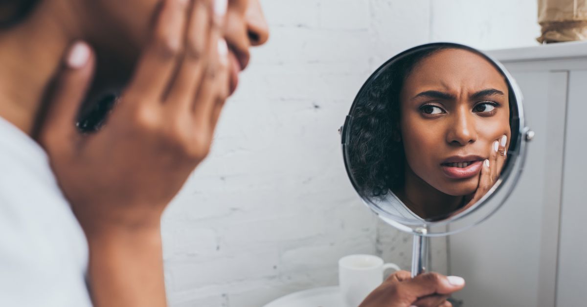 Patient hold small mirror while experiencing dental pain