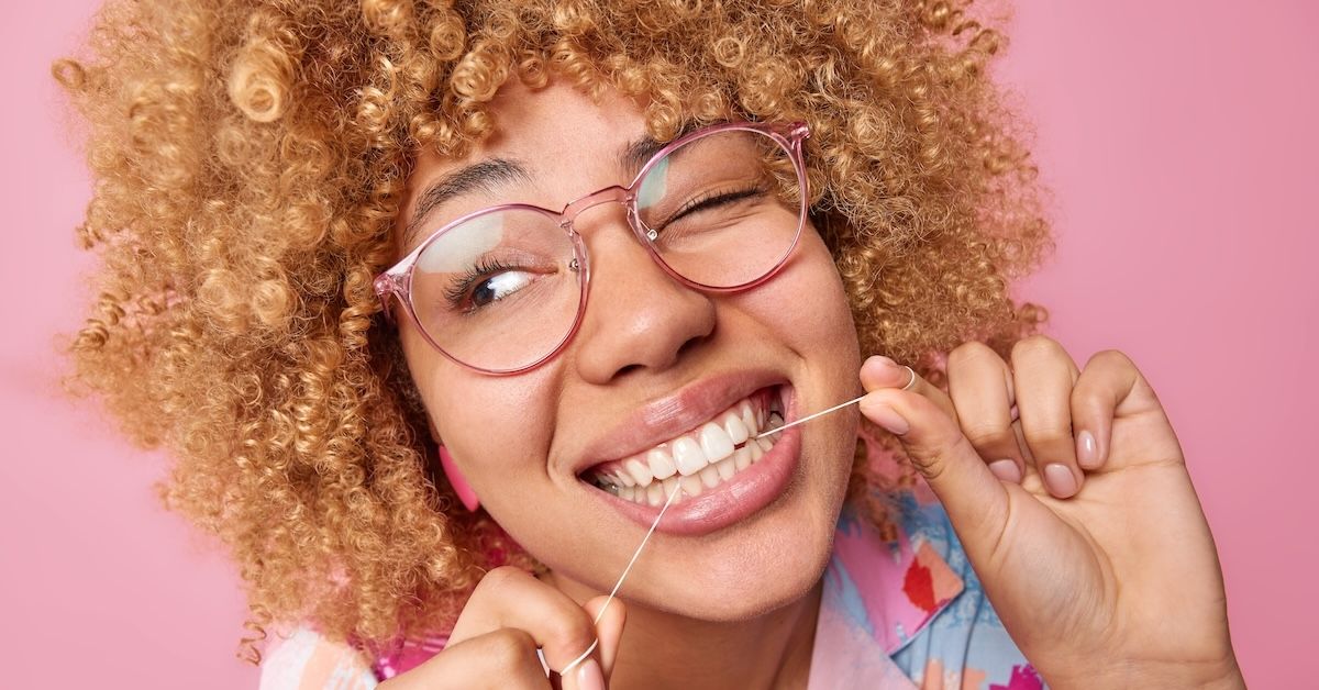 Young black woman flossing her teeth