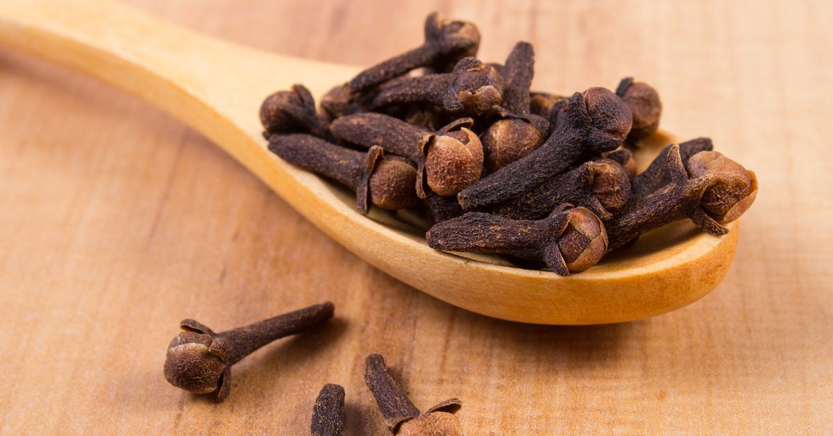 Una cuchara llena de clavos de olor para hacer un colutorio casero natural que cuida tu salud bucal sin dañarla.