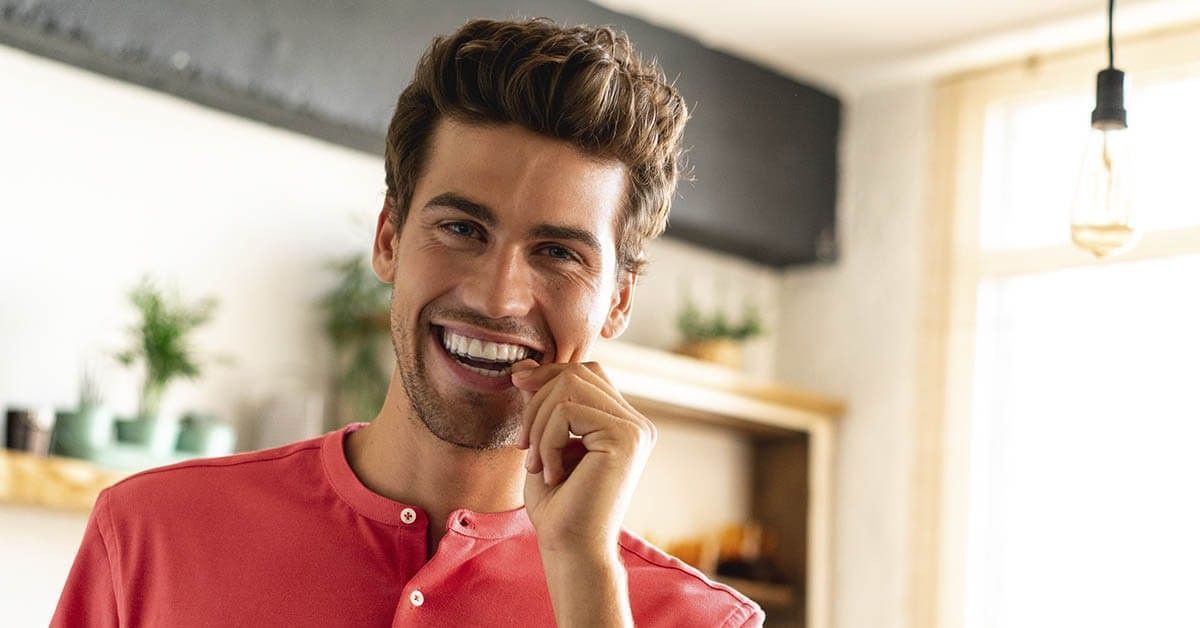 Patient smiling while putting in his orthodontic splints