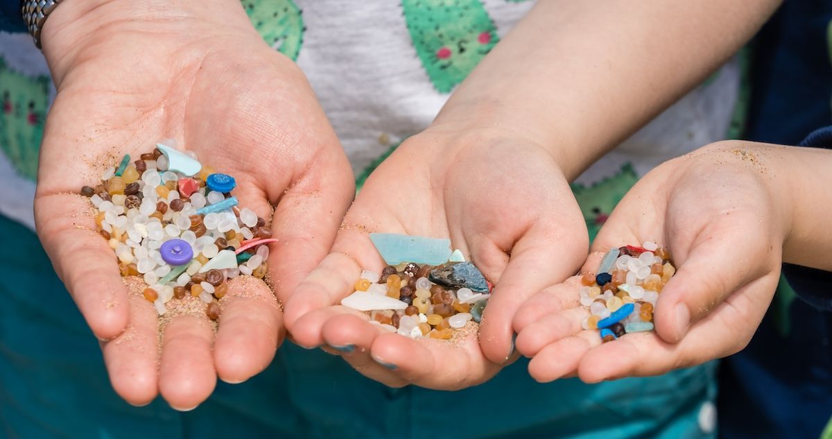 een foto van handen met microplastics, gevonden op het strand