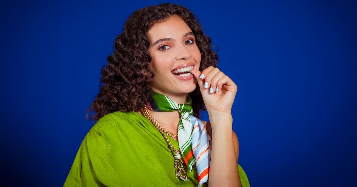 Meisje plaatst zijn onzichtbare aligners met zijn duimen met blauwe achergrond