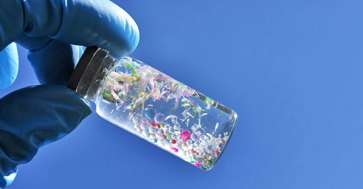 Una mano con un guante que sostiene un bote con microplásticos haciendo referencia a los que pueden contenter los alineadores invisibles.