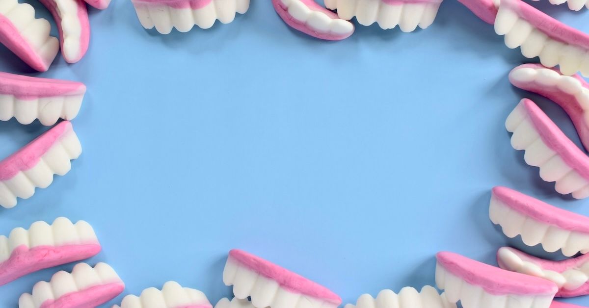 Gummy teeth sweets in a circle against powder blue background