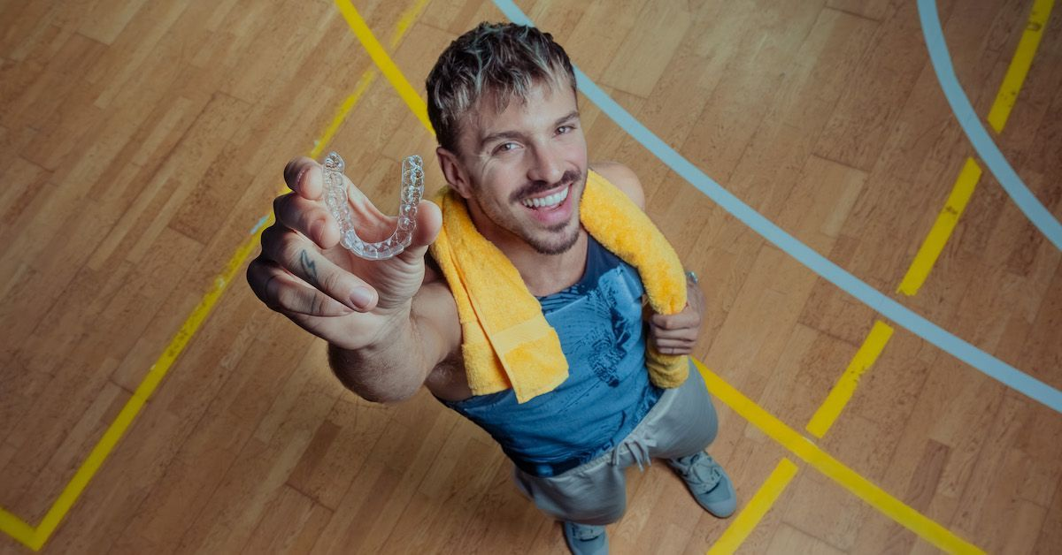 junger Mann hält eine transparente Zahnschiene nach oben