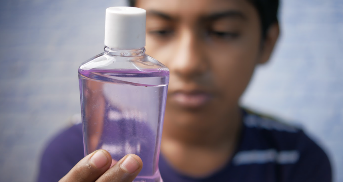 Junge schaut sich eine Flasche mit Mundspülung an
