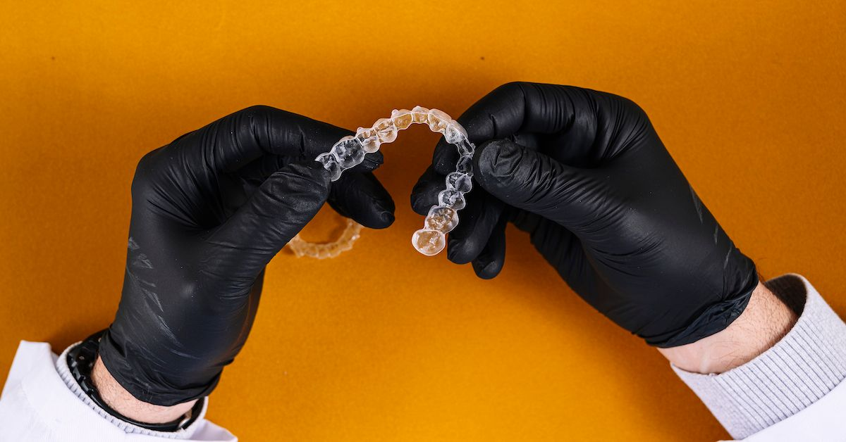 eine unsichtbare Zahnschiene wird in der Hand gehalten