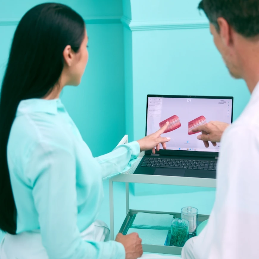 Ärztin und Arzt schauen sich ein Gebiss auf dem Laptop an