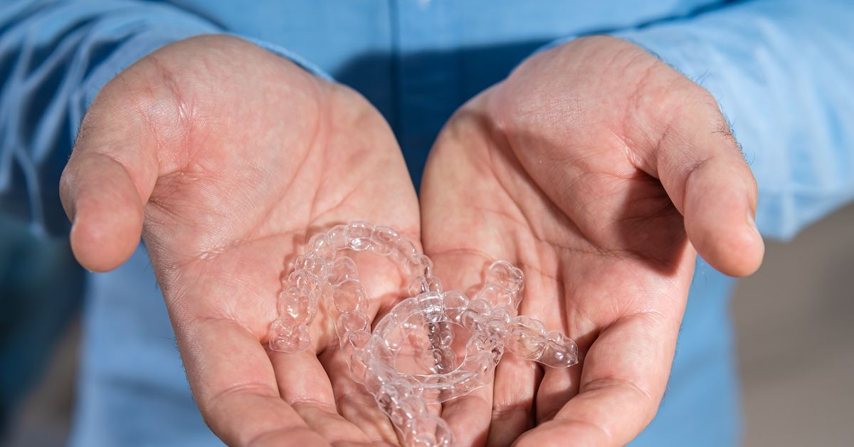 Transparente Zahnschienen werden in den Händen gehalten.