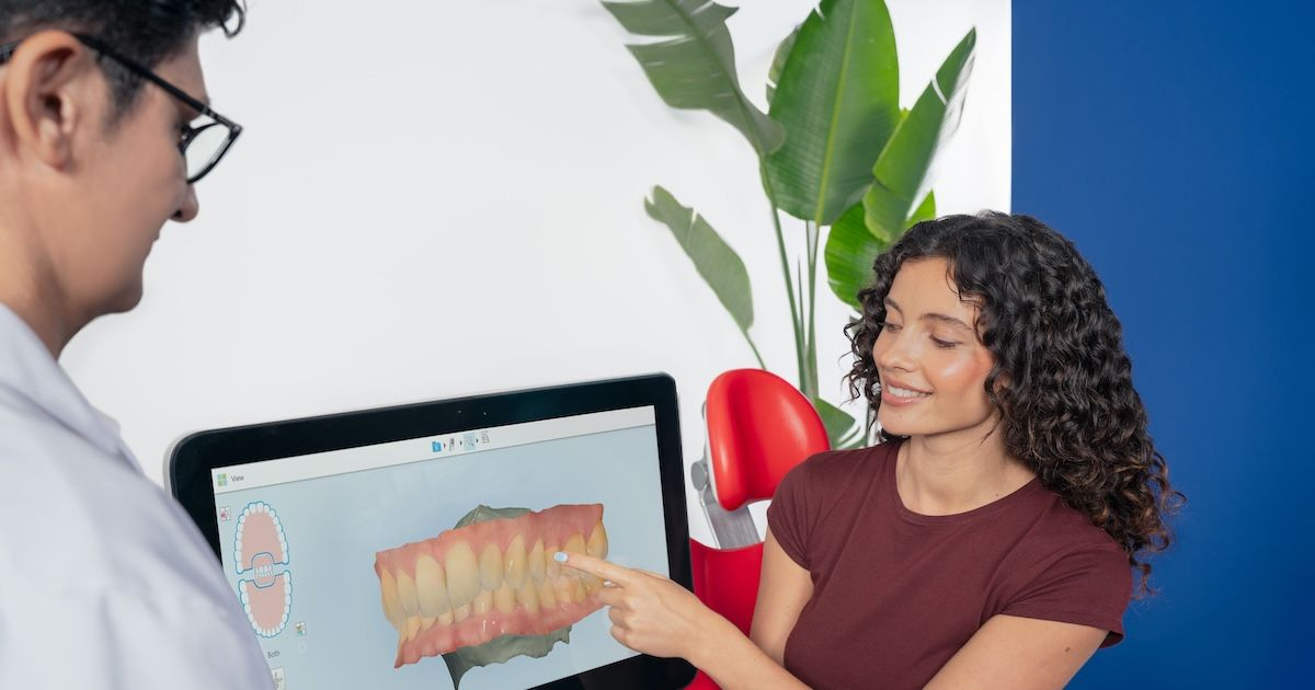 Zahnarzt und Patientin schauen sich gemeinsam den 3D Scan ihrer Zähne auf einem Bildschirm an