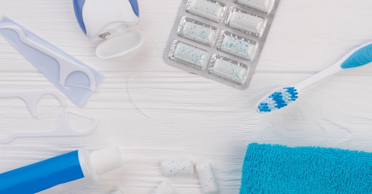 Produkte für eine optimale Mundhygiene wie Zahnseide, eine Zahnbürste und Zahnpasta