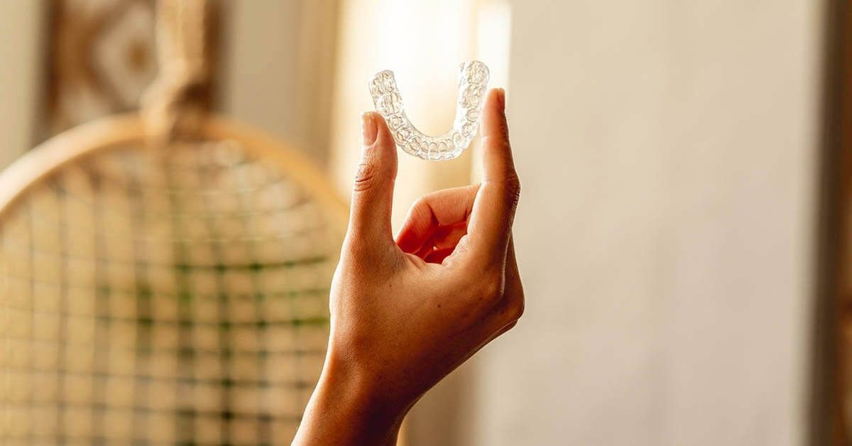 Durchsichtige Zahnschienen werden in einer Hand hochgehalten