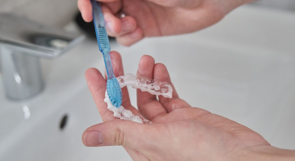 eine transparente Zahnschiene wird mit einer Zahnbürste gereinigt