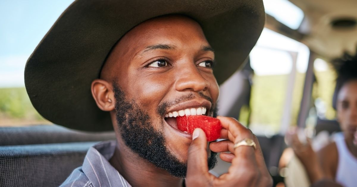 junger Mann beißt in ein Stück Wassermelone