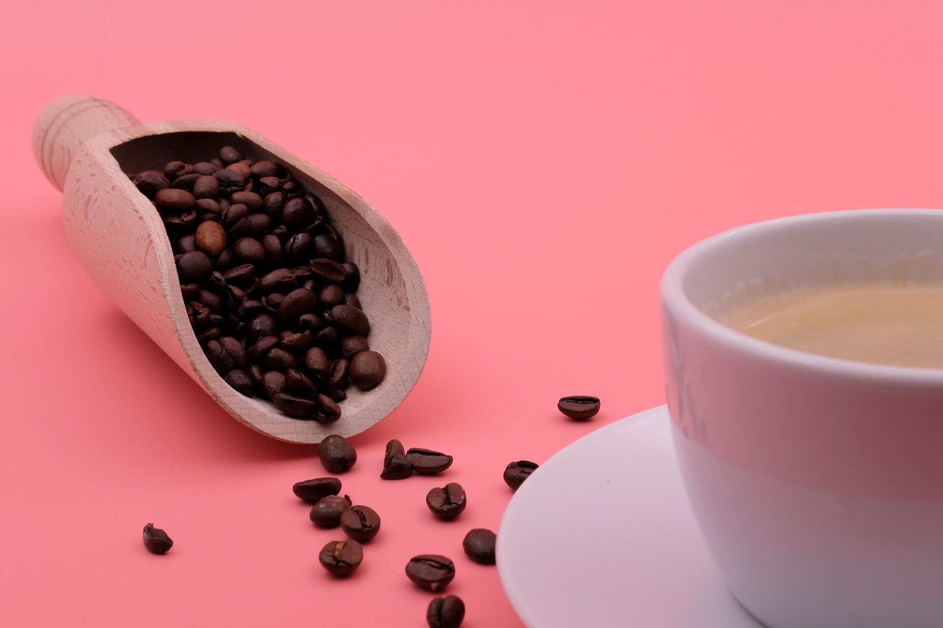 Kaffeebohnen liegen verstreut neben einer Tasse Kaffee