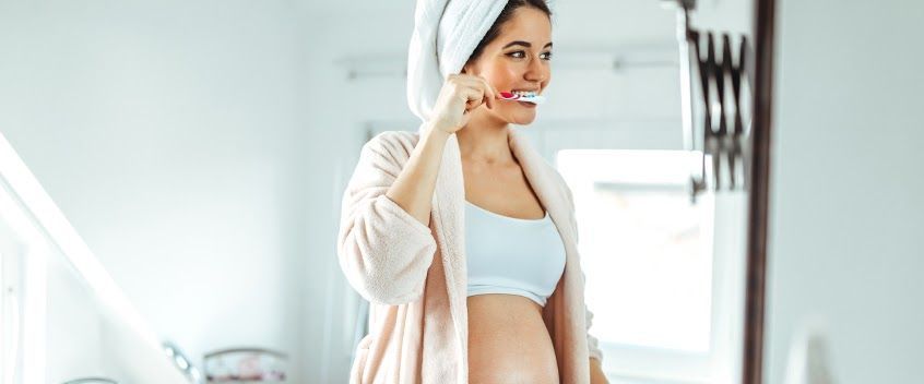 Een zwangere vrouw die haar tanden poetst 