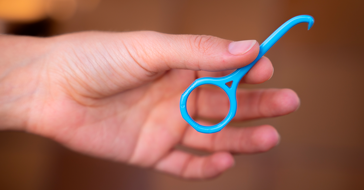 Een hand die een outie vasthoudt. Dit is een tool om je aligners te verwijderen