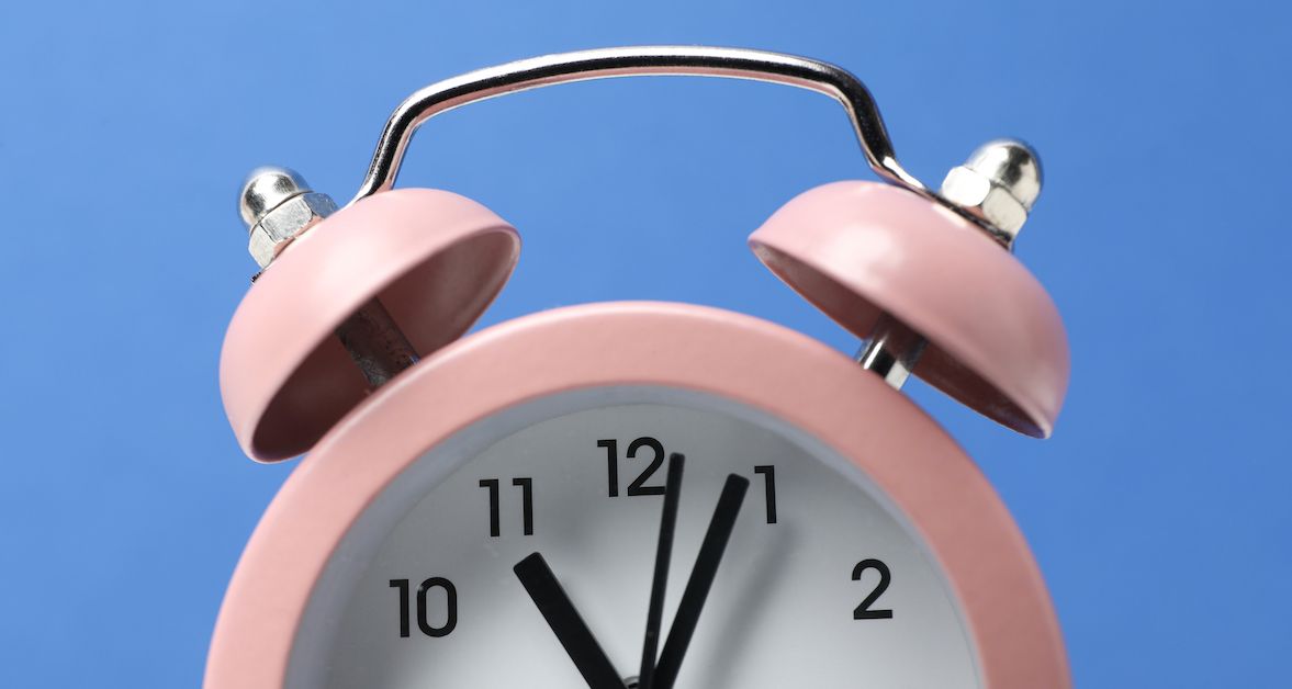 Reloj rosa sobre fondo azul que representa la duración de la ortodoncia.