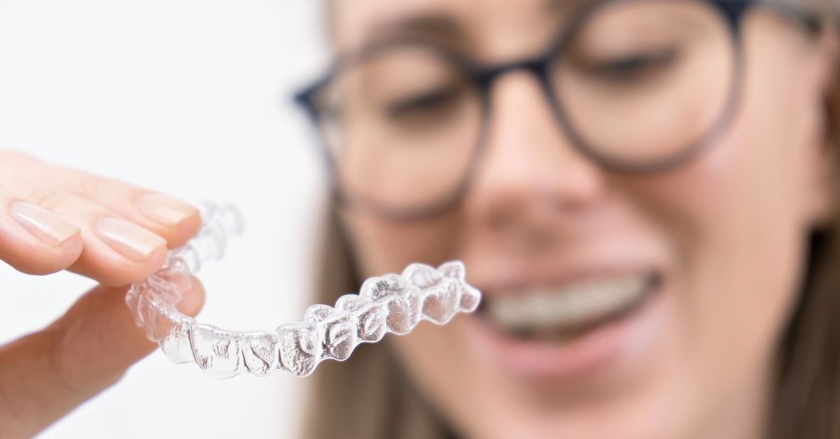 Patiënt die haar uitneembare orthodontische beugel dicht bij de camera vasthoudt.