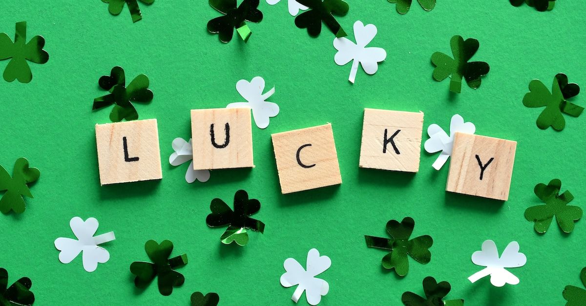Scrabble letters on a green background with clover shapes, spelling 'LUCKY'