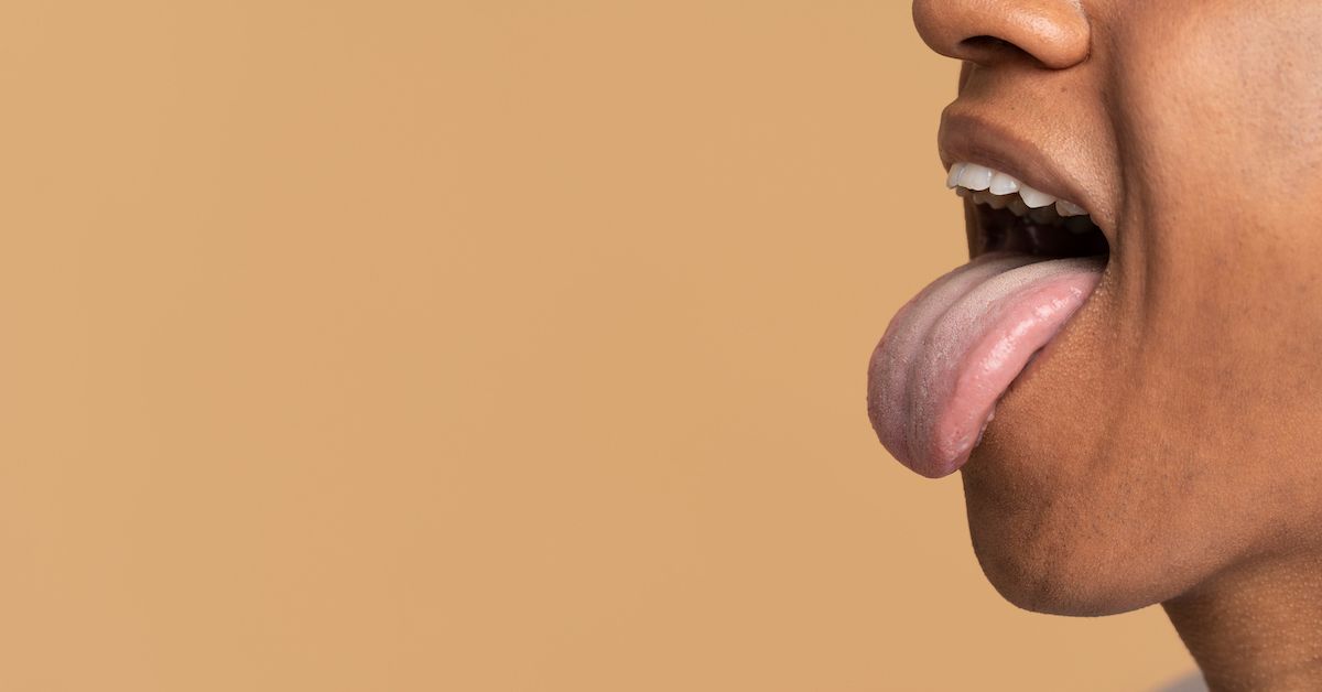 A man sticking his tongue out to show the state of a healthy tongue.