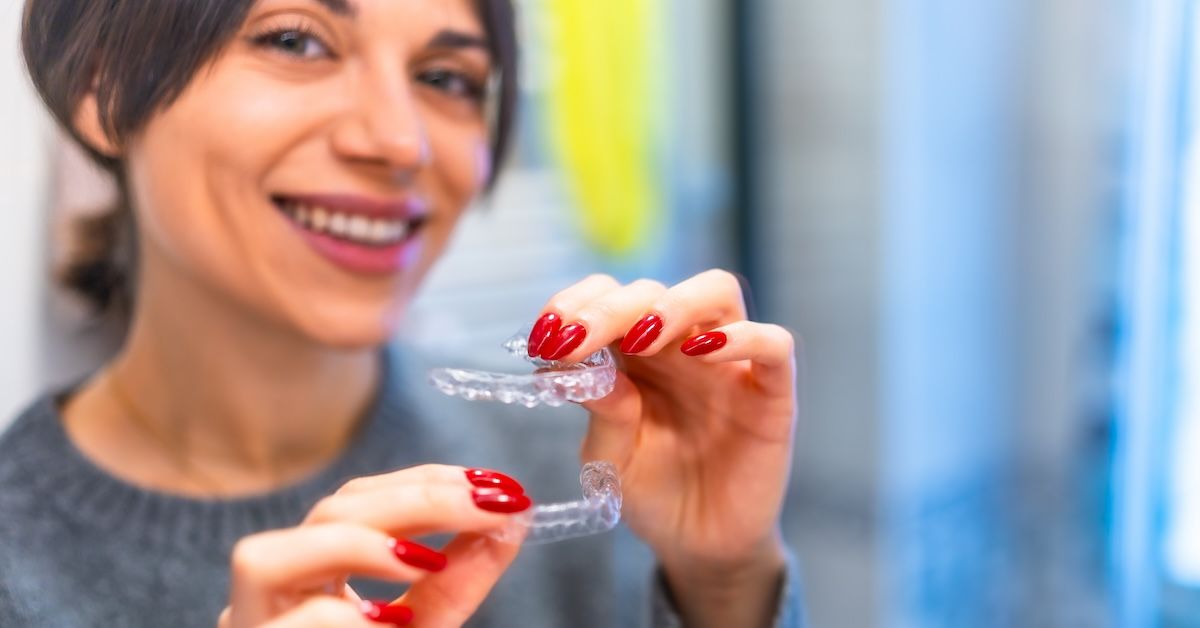 Smiling woman holding aligners