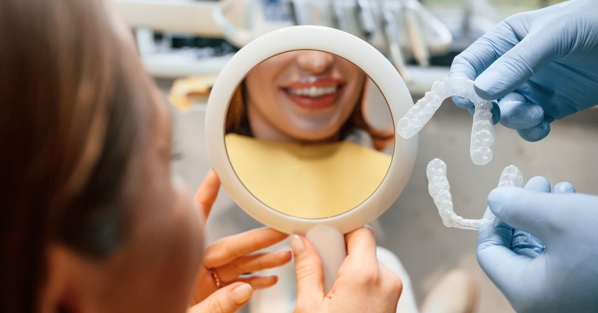 Patient looking at her reflection while positioning aligners in the clinic