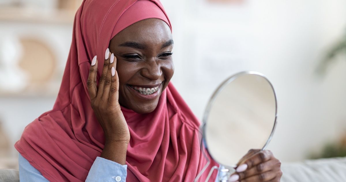 Patiënt die haar glimlach met zelfligerende beugels in de spiegel ziet 