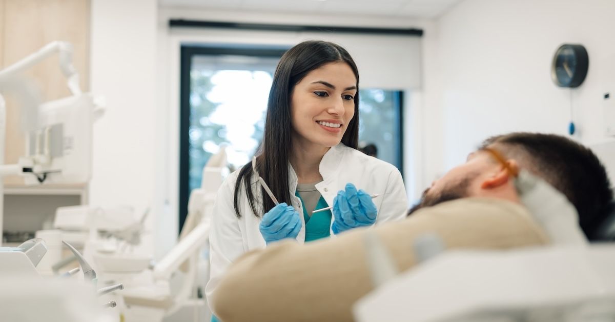 Female orthodontist holding dental tools and looking at patient