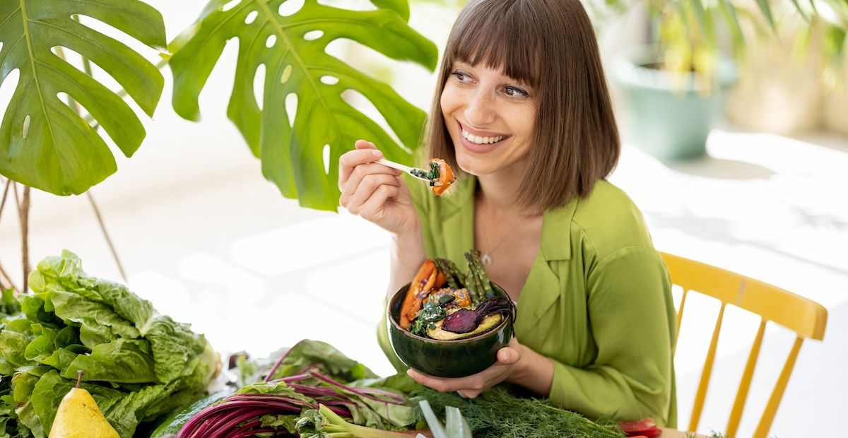 Een vrouw die blij haar groentes eet met een vork