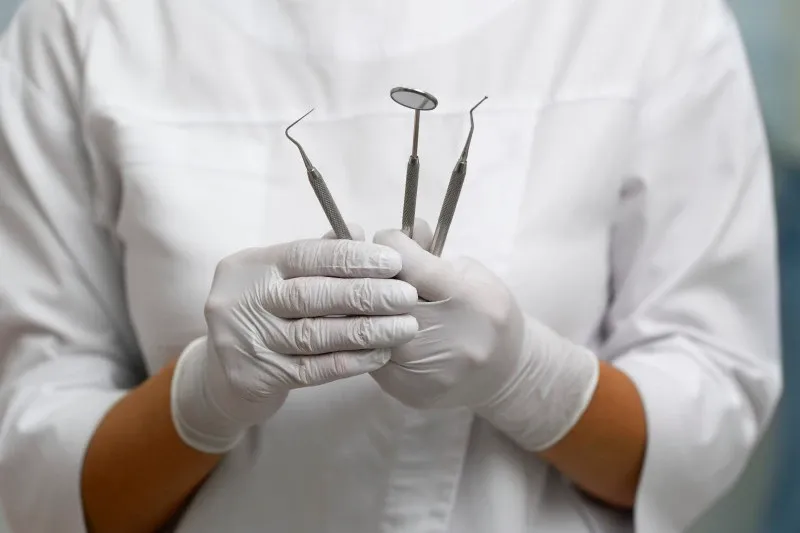 ein Zahnarzt hält die wichtigsten Utensilien für eine Behandlung in der Hand